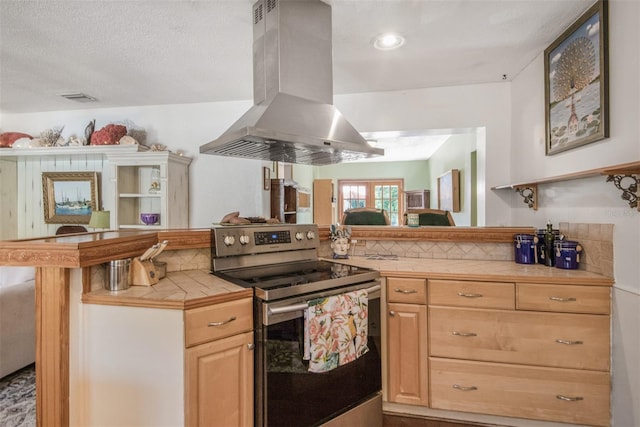 kitchen featuring stainless steel electric range oven, light brown cabinets, tile countertops, kitchen peninsula, and island range hood