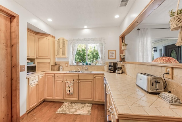 kitchen featuring tile countertops, wood-type flooring, sink, light brown cabinetry, and kitchen peninsula