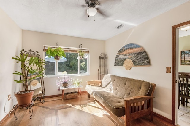 sitting room with wood-type flooring, a textured ceiling, and ceiling fan