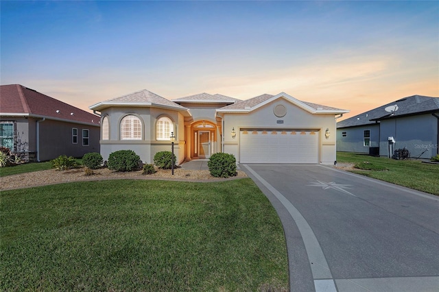 view of front of house with central AC, a garage, and a lawn