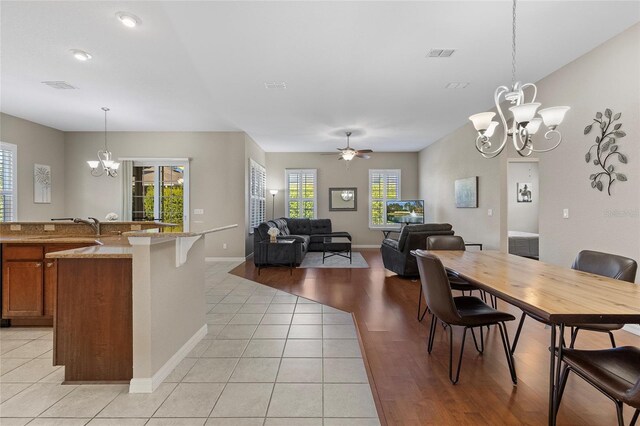 dining space with ceiling fan with notable chandelier, sink, and light tile patterned floors