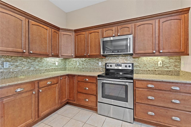 kitchen featuring stainless steel appliances, tasteful backsplash, light stone countertops, and light tile patterned flooring