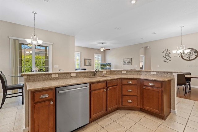 kitchen featuring stainless steel dishwasher, an island with sink, decorative light fixtures, and sink