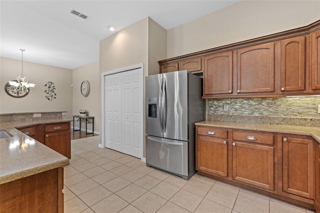 kitchen featuring tasteful backsplash, a chandelier, hanging light fixtures, light tile patterned floors, and stainless steel refrigerator with ice dispenser