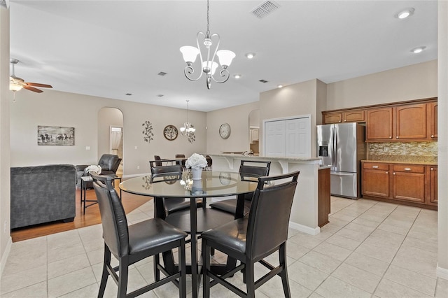 dining area with light tile patterned flooring and ceiling fan with notable chandelier