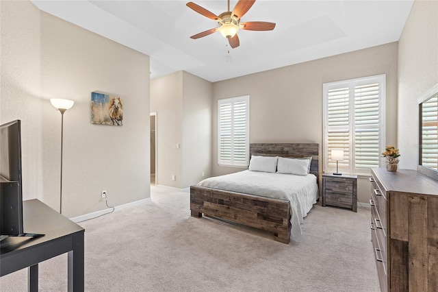 carpeted bedroom with a raised ceiling and ceiling fan