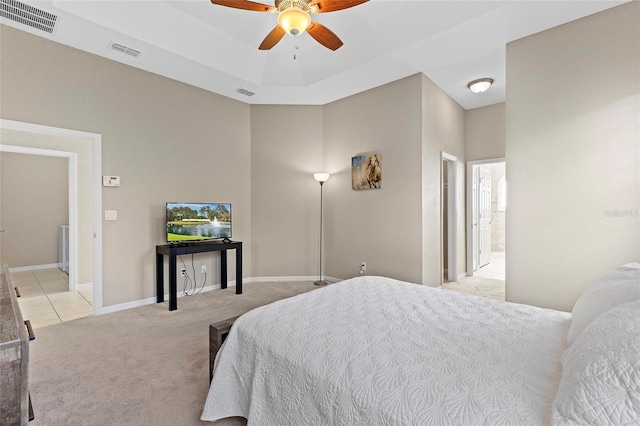 bedroom featuring a tray ceiling, light colored carpet, and ceiling fan