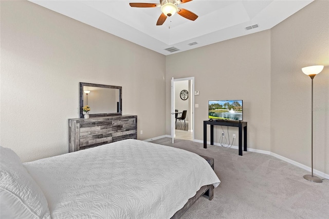 carpeted bedroom featuring ceiling fan and a tray ceiling