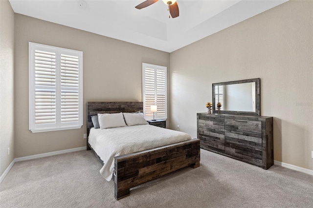 bedroom featuring ceiling fan, a raised ceiling, and light carpet