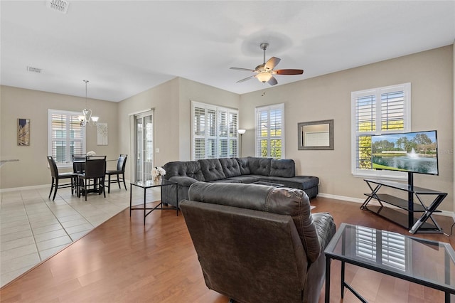 living room with ceiling fan with notable chandelier and wood-type flooring