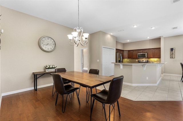 dining area with light hardwood / wood-style flooring and a chandelier