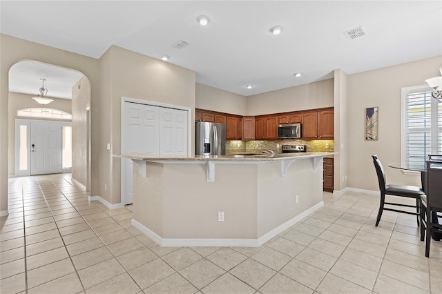 kitchen featuring stainless steel appliances, a breakfast bar area, a center island with sink, and light tile patterned floors