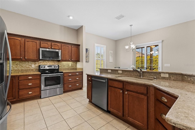 kitchen featuring sink, light tile patterned floors, appliances with stainless steel finishes, backsplash, and decorative light fixtures