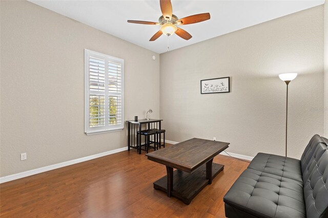 sitting room with dark wood-type flooring and ceiling fan