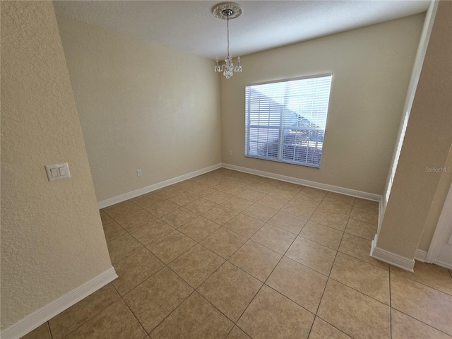 spare room with light tile patterned floors and an inviting chandelier