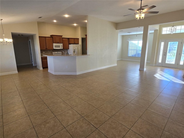 kitchen with backsplash, light stone counters, ceiling fan with notable chandelier, white appliances, and decorative light fixtures