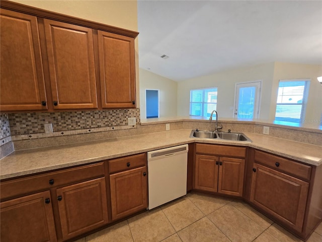 kitchen with backsplash, white dishwasher, lofted ceiling, and sink