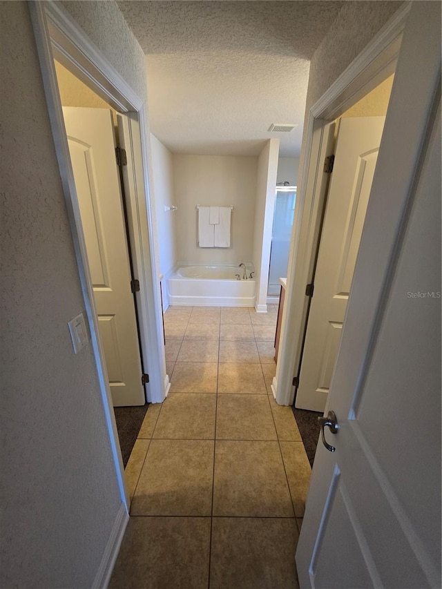 corridor featuring light tile patterned floors and a textured ceiling