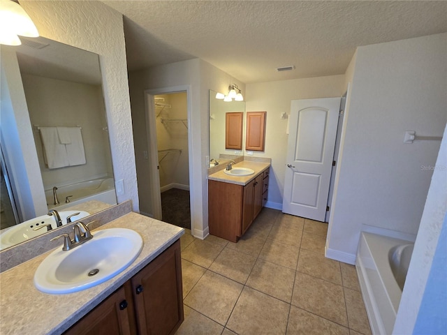 bathroom featuring tile patterned flooring, vanity, a bathtub, and a textured ceiling