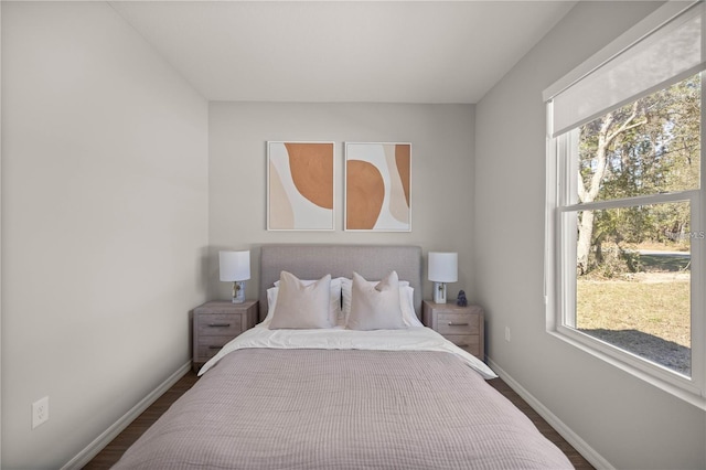 bedroom with multiple windows and dark hardwood / wood-style floors