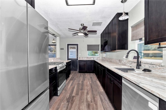 kitchen featuring a textured ceiling, appliances with stainless steel finishes, sink, hanging light fixtures, and ceiling fan