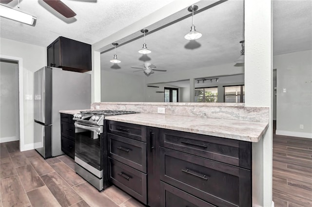 kitchen with light stone countertops, a textured ceiling, decorative light fixtures, stainless steel appliances, and kitchen peninsula