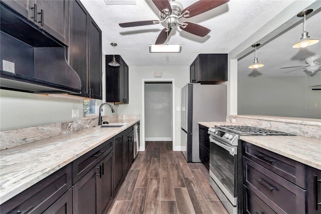 kitchen featuring a textured ceiling, stainless steel appliances, sink, hanging light fixtures, and ceiling fan