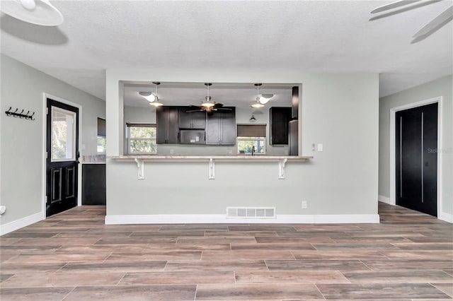 kitchen with stainless steel refrigerator, kitchen peninsula, pendant lighting, and a kitchen breakfast bar