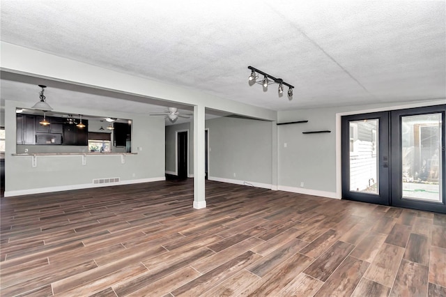 unfurnished living room featuring ceiling fan, rail lighting, a wealth of natural light, and french doors