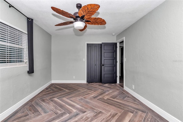 unfurnished bedroom featuring a closet, ceiling fan, dark parquet floors, and a textured ceiling