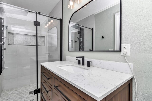 bathroom featuring a shower with shower door and vanity