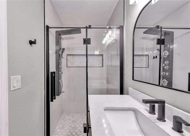 bathroom featuring a shower with door and vanity