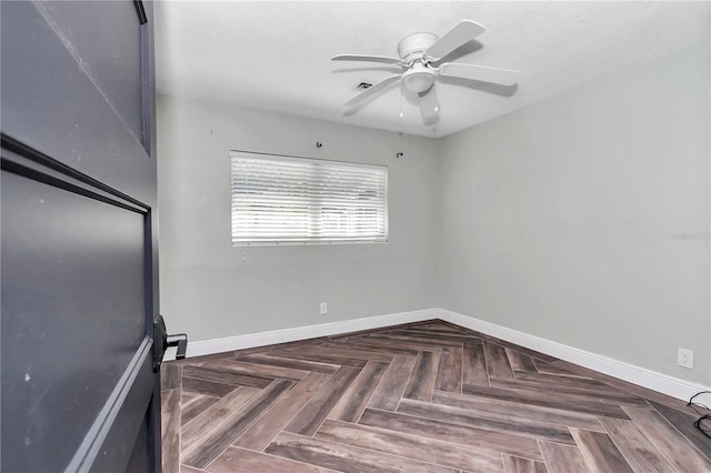 unfurnished room featuring ceiling fan and dark parquet flooring