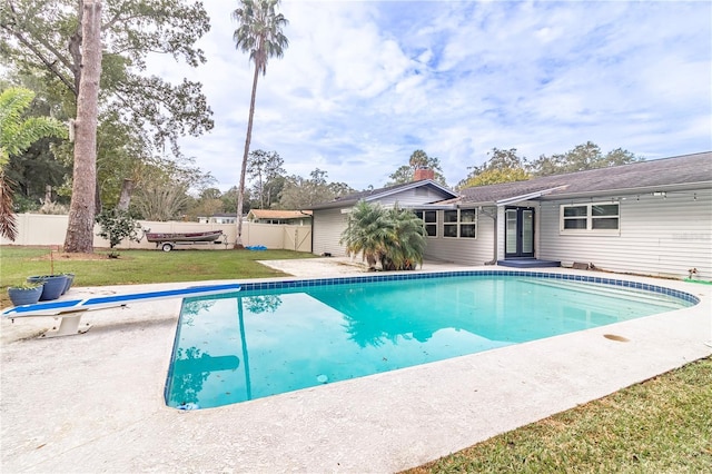 view of pool with a diving board and a yard