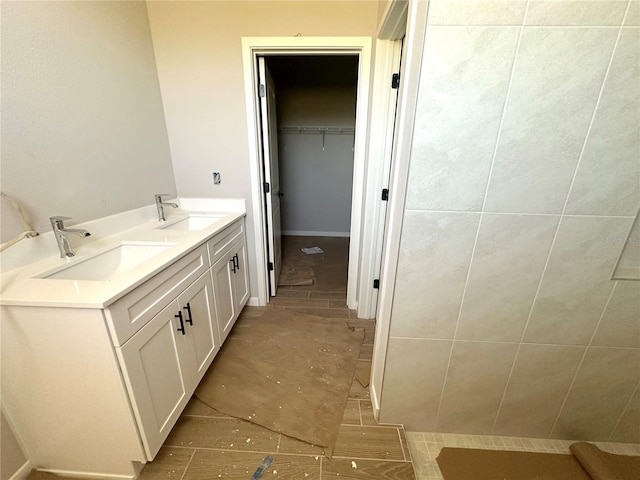 bathroom featuring double vanity, a sink, and a walk in closet