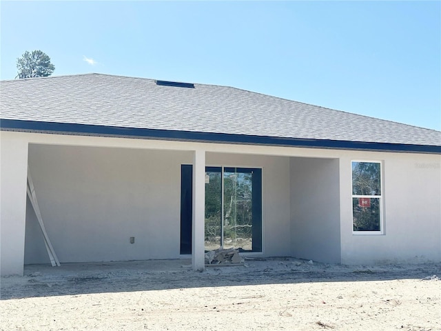 back of property featuring roof with shingles and stucco siding