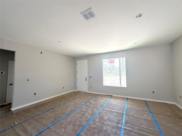 spare room with a textured ceiling, visible vents, and baseboards