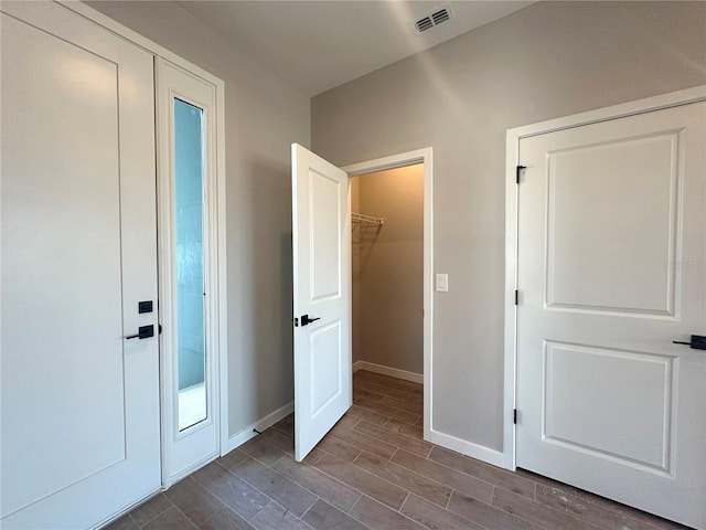 unfurnished bedroom with dark wood-style floors, visible vents, and baseboards