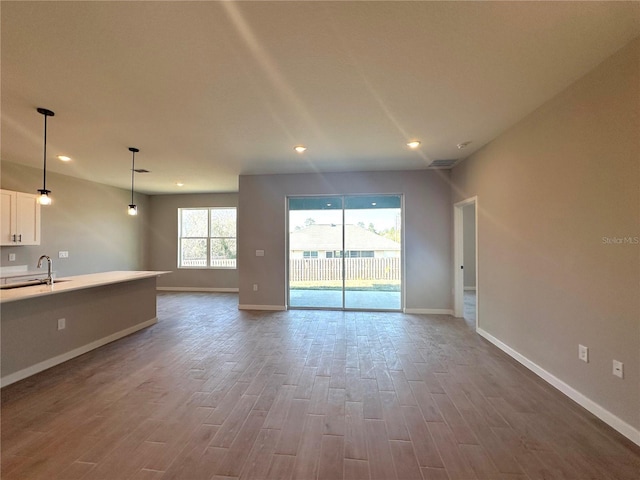 unfurnished living room with dark wood-style flooring, a sink, and baseboards