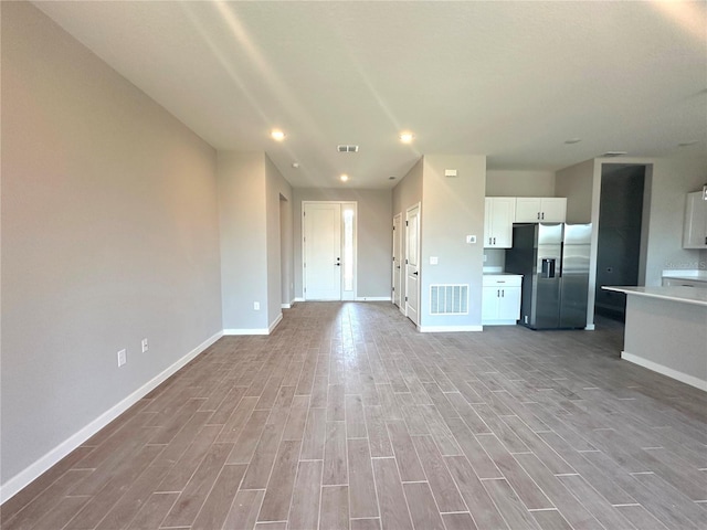 unfurnished living room featuring light wood finished floors, baseboards, and visible vents