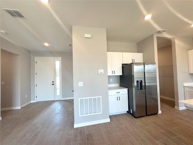 kitchen with wood finished floors, stainless steel fridge, and visible vents