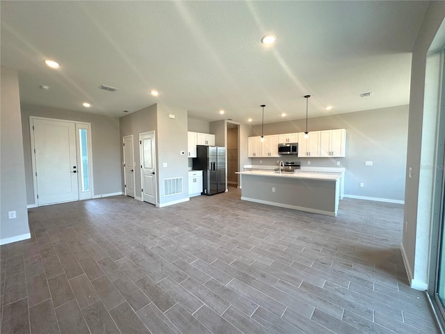 kitchen with visible vents, appliances with stainless steel finishes, open floor plan, and wood finish floors