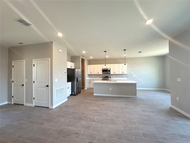 kitchen featuring visible vents, white cabinets, an island with sink, appliances with stainless steel finishes, and open floor plan