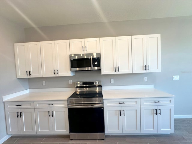 kitchen featuring appliances with stainless steel finishes, light countertops, white cabinetry, and baseboards