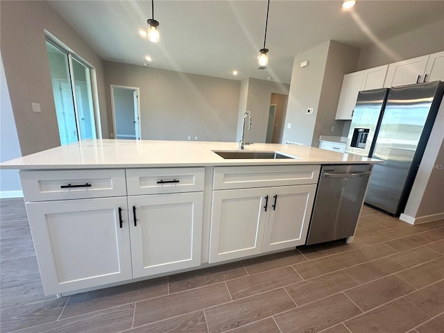 kitchen featuring pendant lighting, stainless steel appliances, wood tiled floor, white cabinetry, and a sink