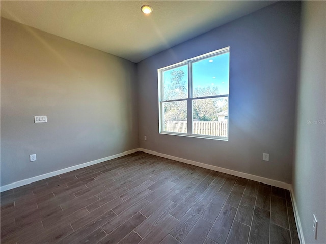 empty room featuring baseboards and dark wood-style flooring