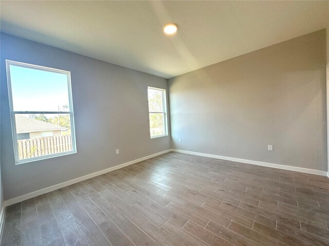 spare room with baseboards and dark wood-style flooring