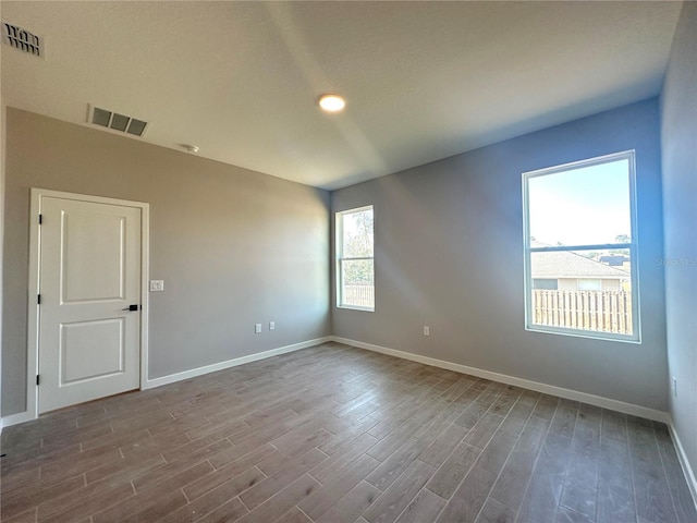 empty room featuring baseboards, visible vents, and wood finished floors