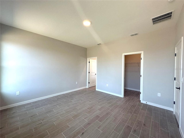 unfurnished room featuring baseboards, visible vents, and wood tiled floor