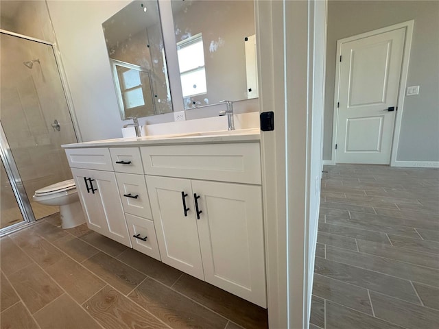 bathroom featuring toilet, wood finish floors, a sink, a shower stall, and double vanity